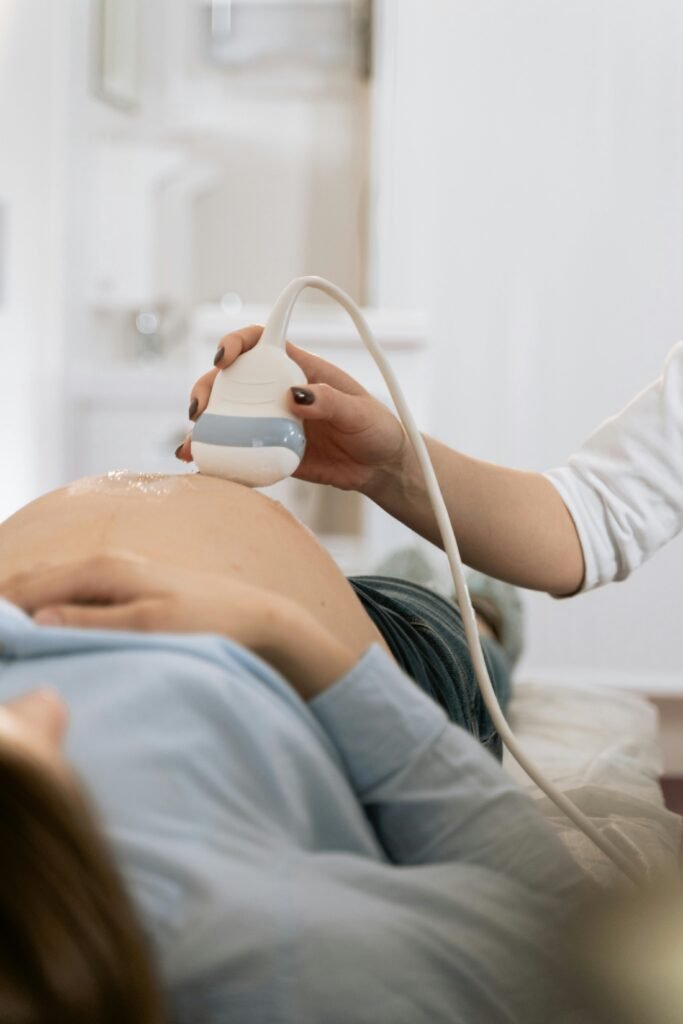 A pregnant woman undergoing a medical ultrasound in a clinical setting.